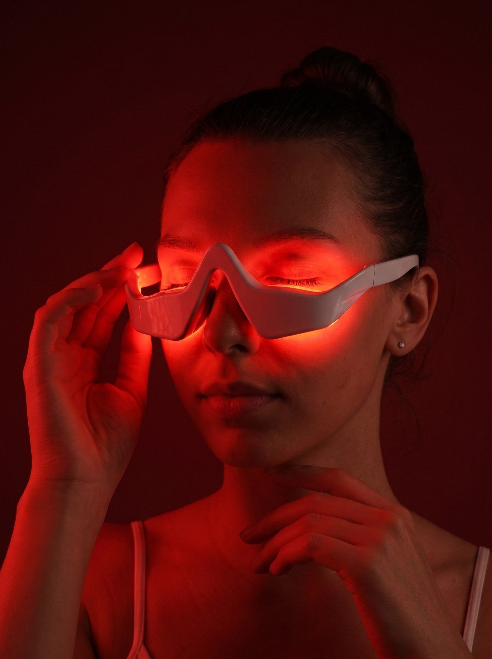 Woman wearing GoodLife red light under-eye glasses with the LEDs glowing